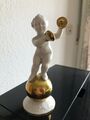 Porzellanfigur Putto mit Schellen auf Goldkugel